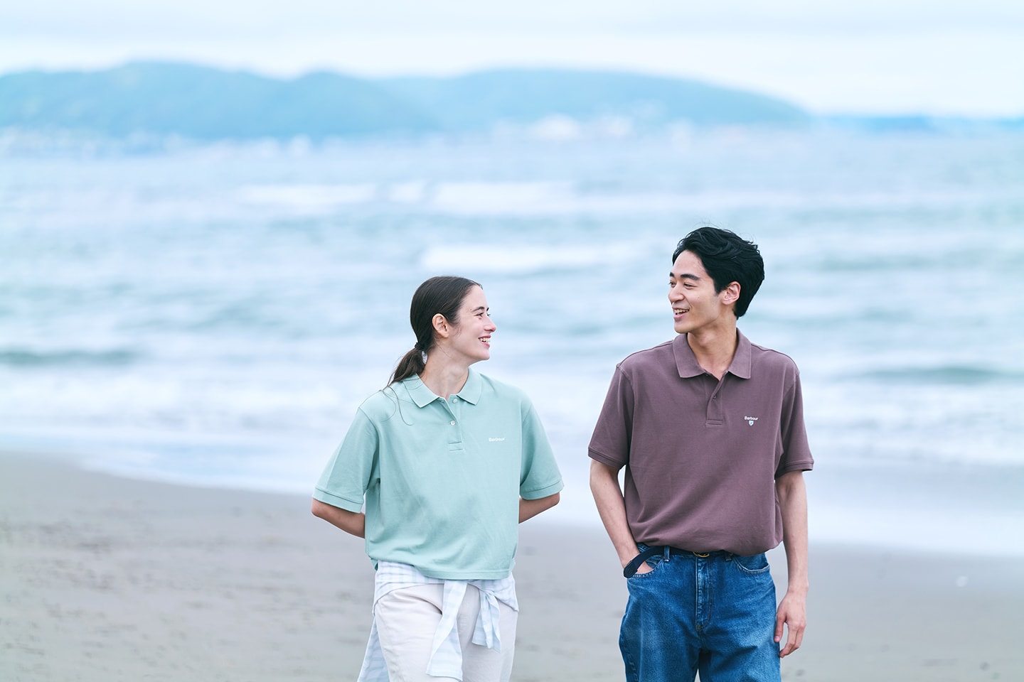 海辺で女性と男性が談笑している画像