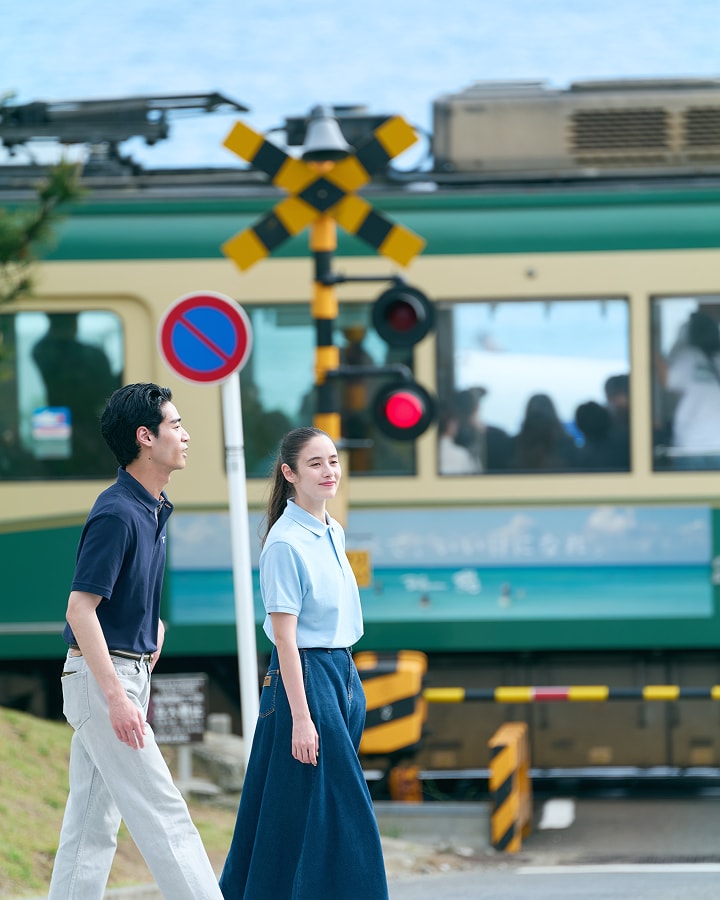 江ノ電の前を歩いている男女